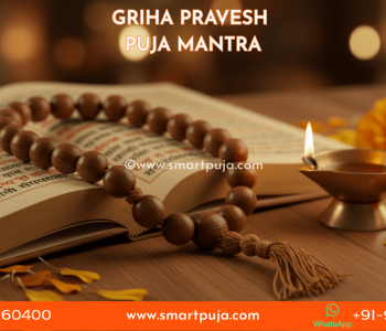 Griha Pravesh Puja Mantra - Close-up of a Hindu sacred text and a wooden Japa Mala illuminated by a brass oil lamp.